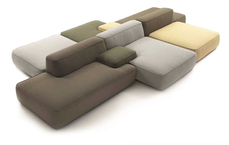 Ett modulärt soffset som består av jordnära delar, inklusive grönt, brunt, beige och grått, arrangerat i en pusselliknande formation på en vit bakgrund – perfekt fångar den eleganta atmosfären i Göteborg.