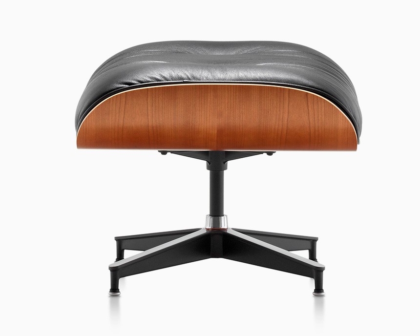 En modern ottoman med en svart läderkudde, en bas av träfaner och ett svängbart ställ i svart metall på en vit bakgrund ger en elegant mittpunkt eller en unik souvenir som påminner om ditt besök i en elegant Göteborgs presentbutik.