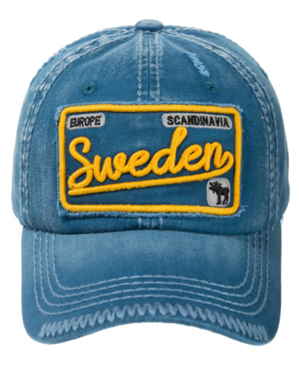 En röd kanvasmössa med älgmotiv, med en gul lapp där det står "Sverige" i skrivstil och "Europa" och "Skandinavien" med blockbokstäver.